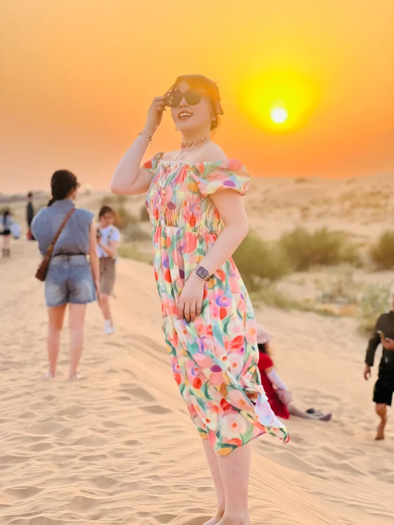 Golden hour in the desert as a woman poses on the sand.
