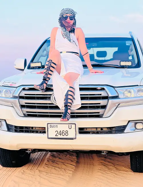 Tourist posing on a 4x4 vehicle during their Dubai desert safari adventure.