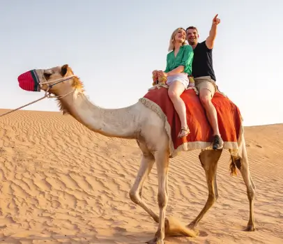 A couple on a traditional camel riding adventure during their Dubai desert safari.