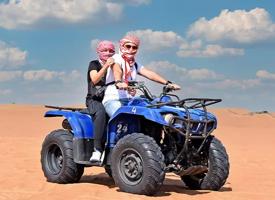 An adventurous couple on a quad bike excursion in the desert.